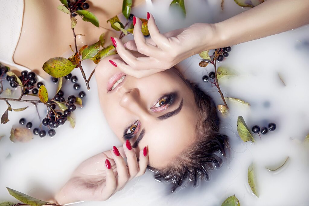 Brunette girl with bright makeup and clean the skin in the milk close-up top view